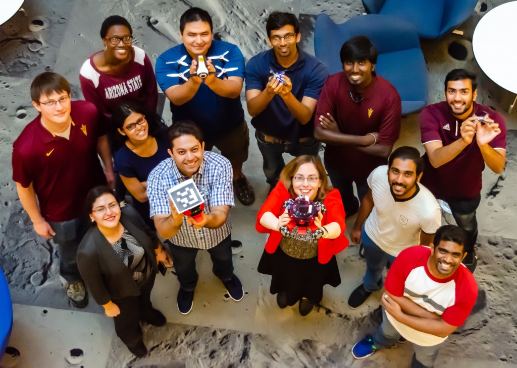ACS Lab group photo from 2018. Camera overhead looking down on lab members holding various robots.