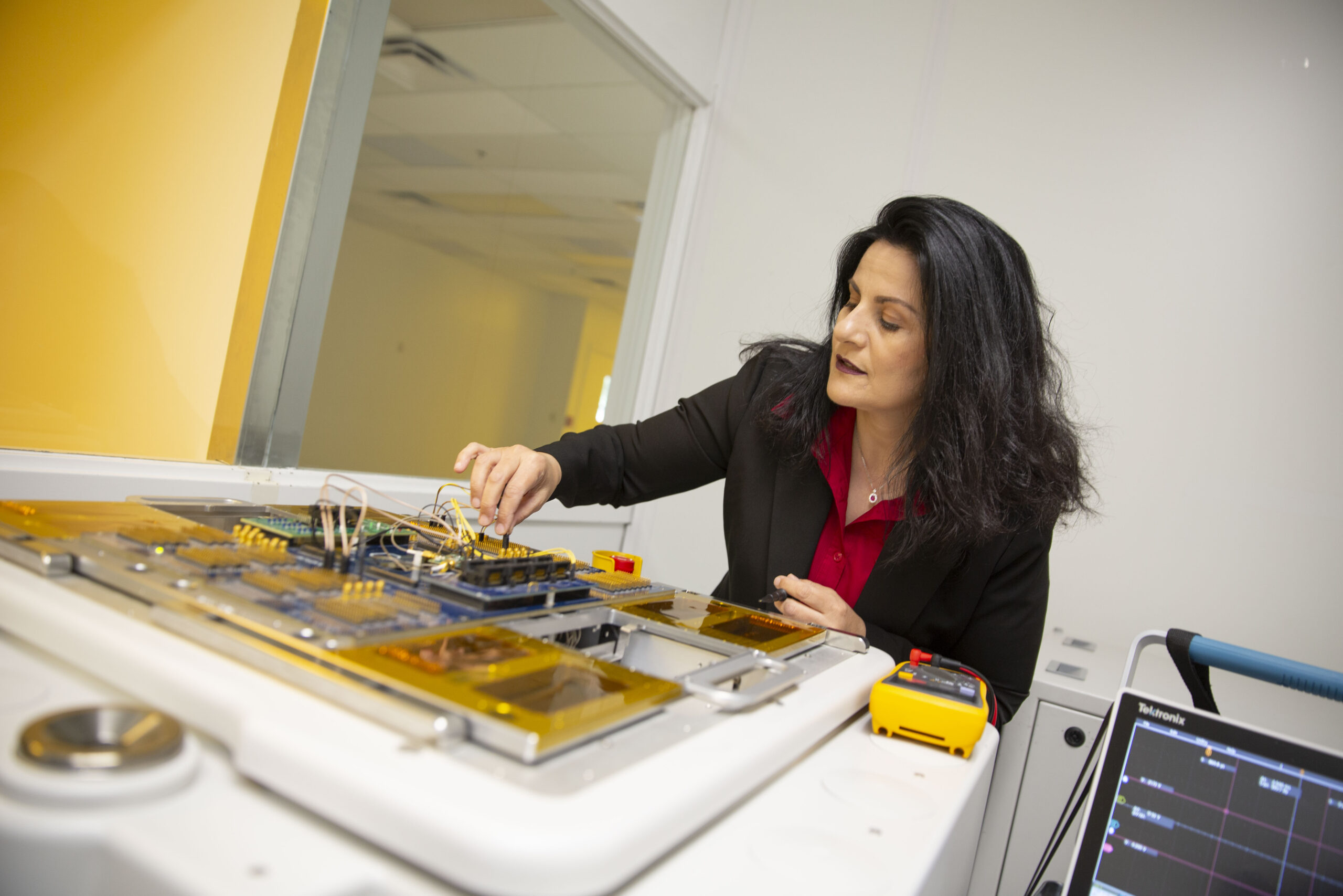 Photo of Sule Ozev manipulating a teaching-sized electrical board in her lab.
